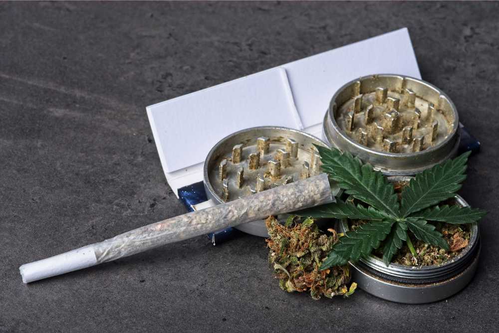 closeup of rolled joint grinder rolling papers cannabis leaf