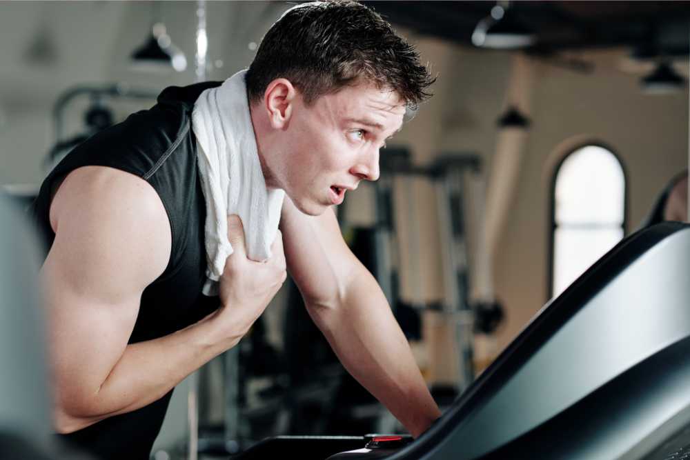 sweaty man exercising with white towel around neck