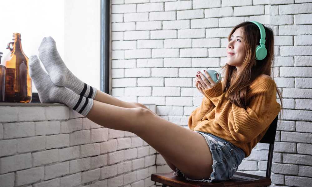 happy woman relaxing feet up with headphones