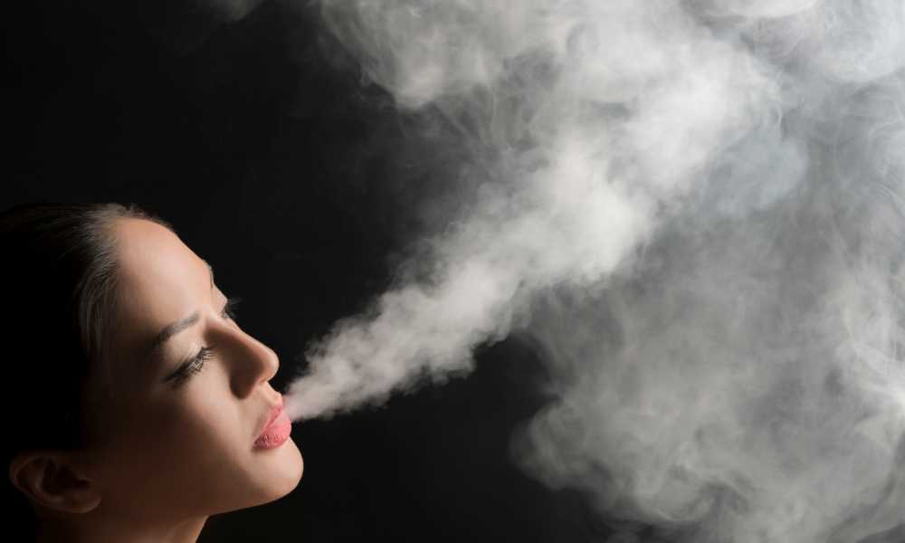 woman exhaling huge cloud of smoke