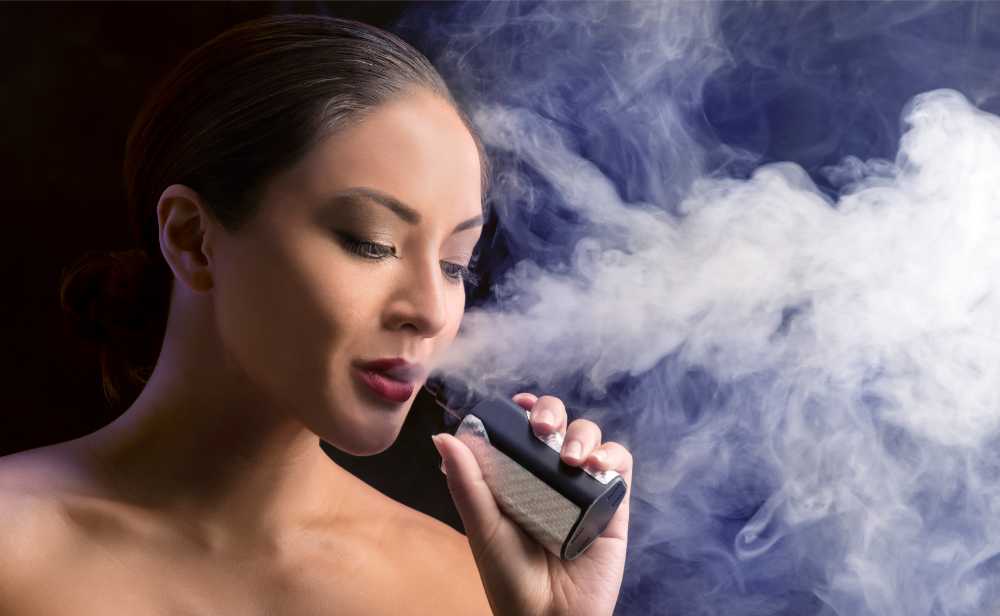 brunette woman vaping massive vapor in background