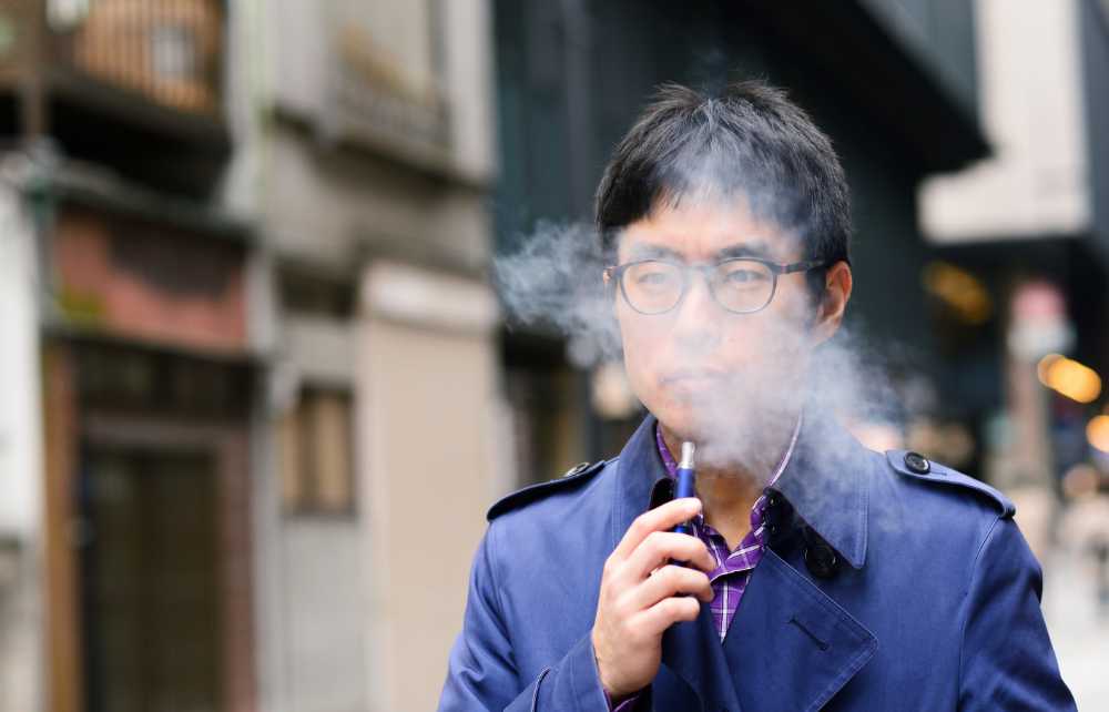 asian man with glasses blue jacket vaping